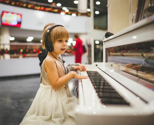 Klein meisje speelt piano met koptelefoon op